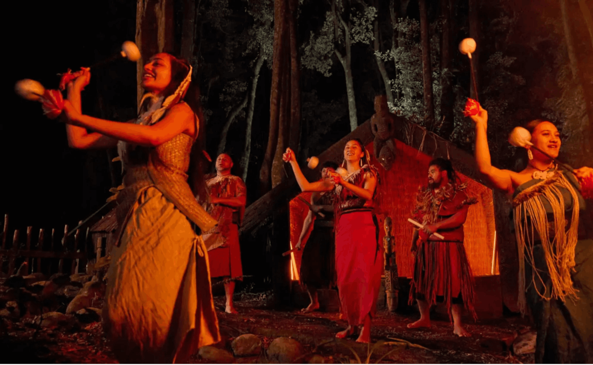 Performers taking part in a Māori cultural evening experience in a forest setting in Rotorua, New Zealand.