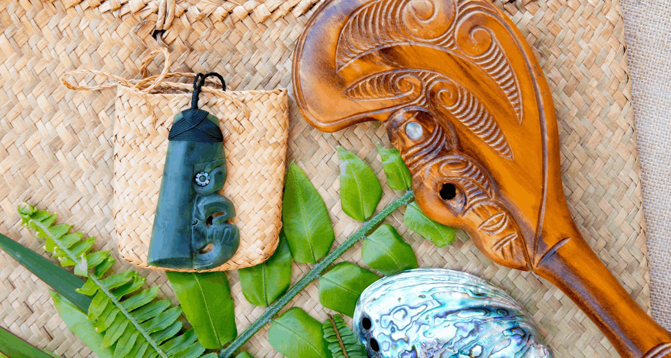 Traditional Māori gift items including a carved wooden object, greenstone pendant, woven flax, and paua shell in New Zealand.